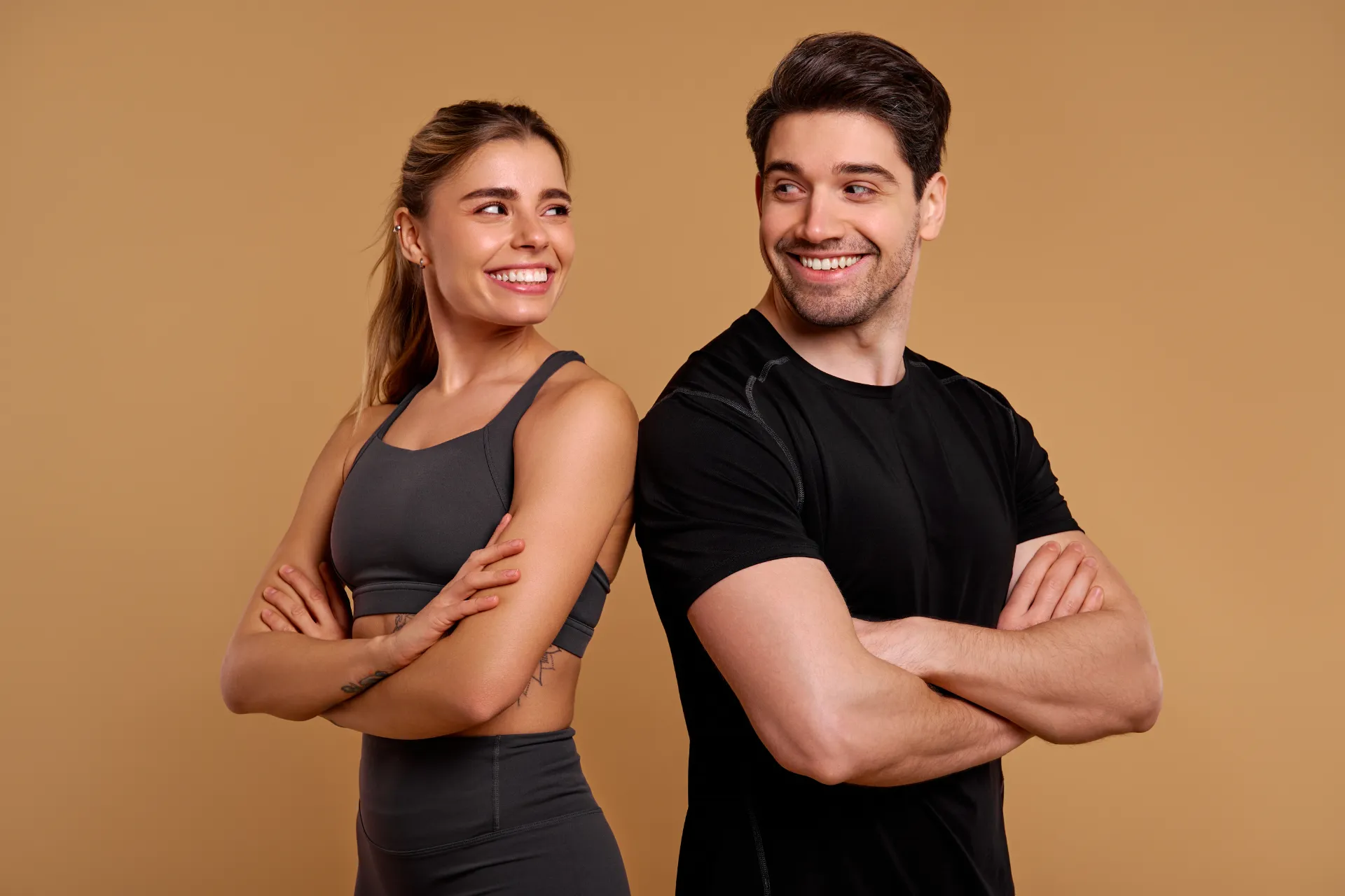 smiling athletic man and woman posing back to back utc